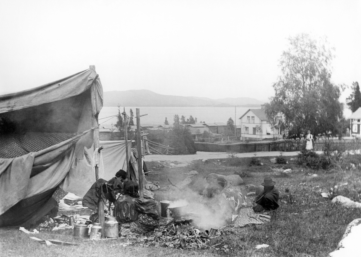 Här syns ett romskt sällskap som slagit läger i en grässlänt. Bilden är troligtvis tagen kring sekelskiftet 1900, men platsen är okänd.