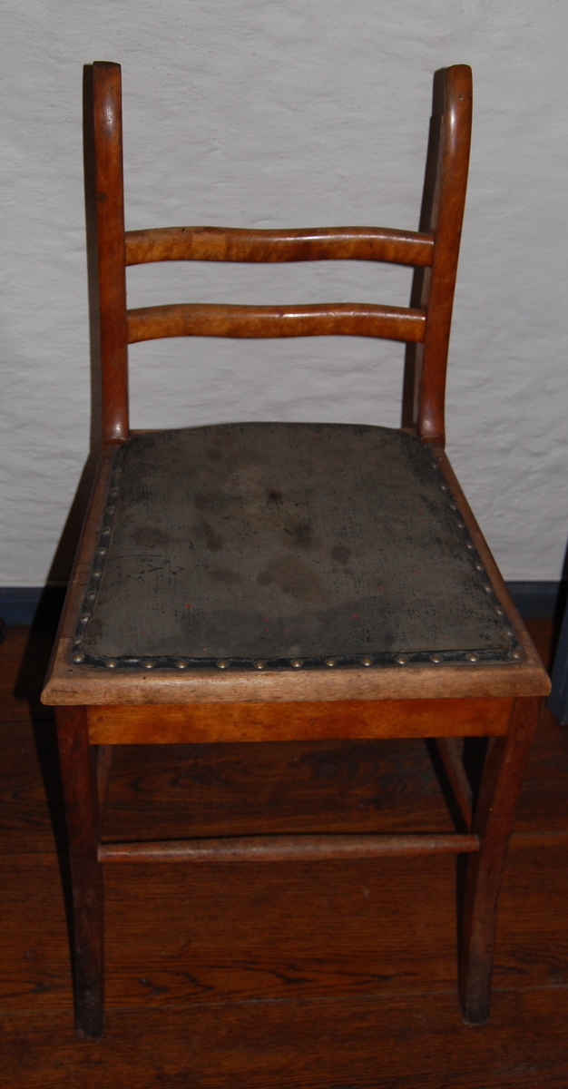 Trestol med setetrekk i kunstskinn (?). Likner AS.613-617, Biedermeier-stil. Mangler øverste ryggsprosse, røde malingsflekker på setet.