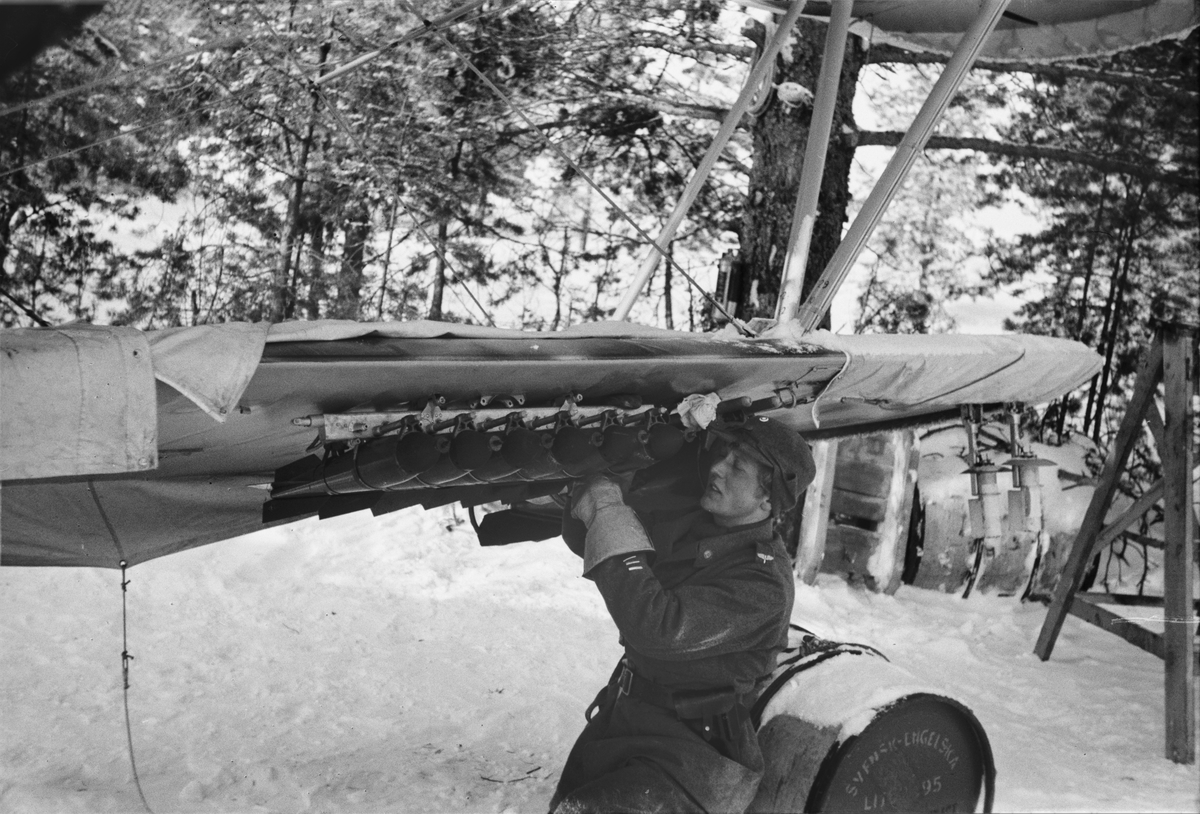 En flygtekniker laddar 12 kg:s bomber på flygplan B 4 Hawker Hart inför flygning den 18 februari 1940. Vid F 19, Svenska frivilligkåren i Finland.
