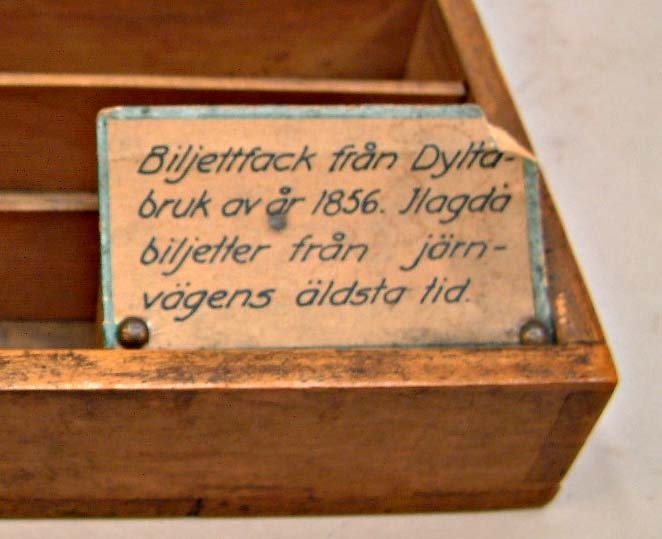 Biljettfack av brunlackerat trä från Dylta bruk av år 1856. Ilagda biljetter från järnvägens äldsta tid.