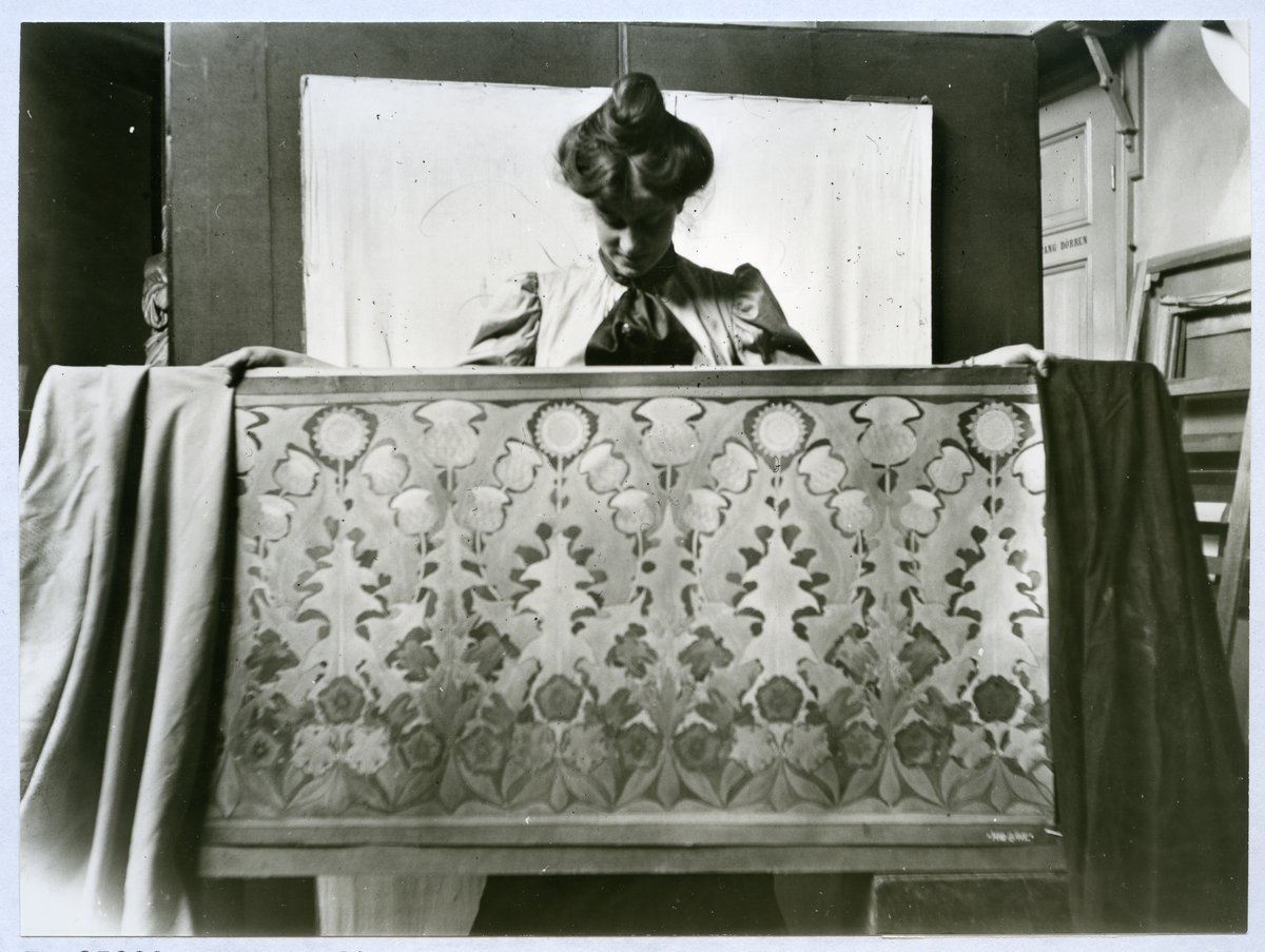 Stockholm. 
Kvinna stående bakom tavla. 1901.