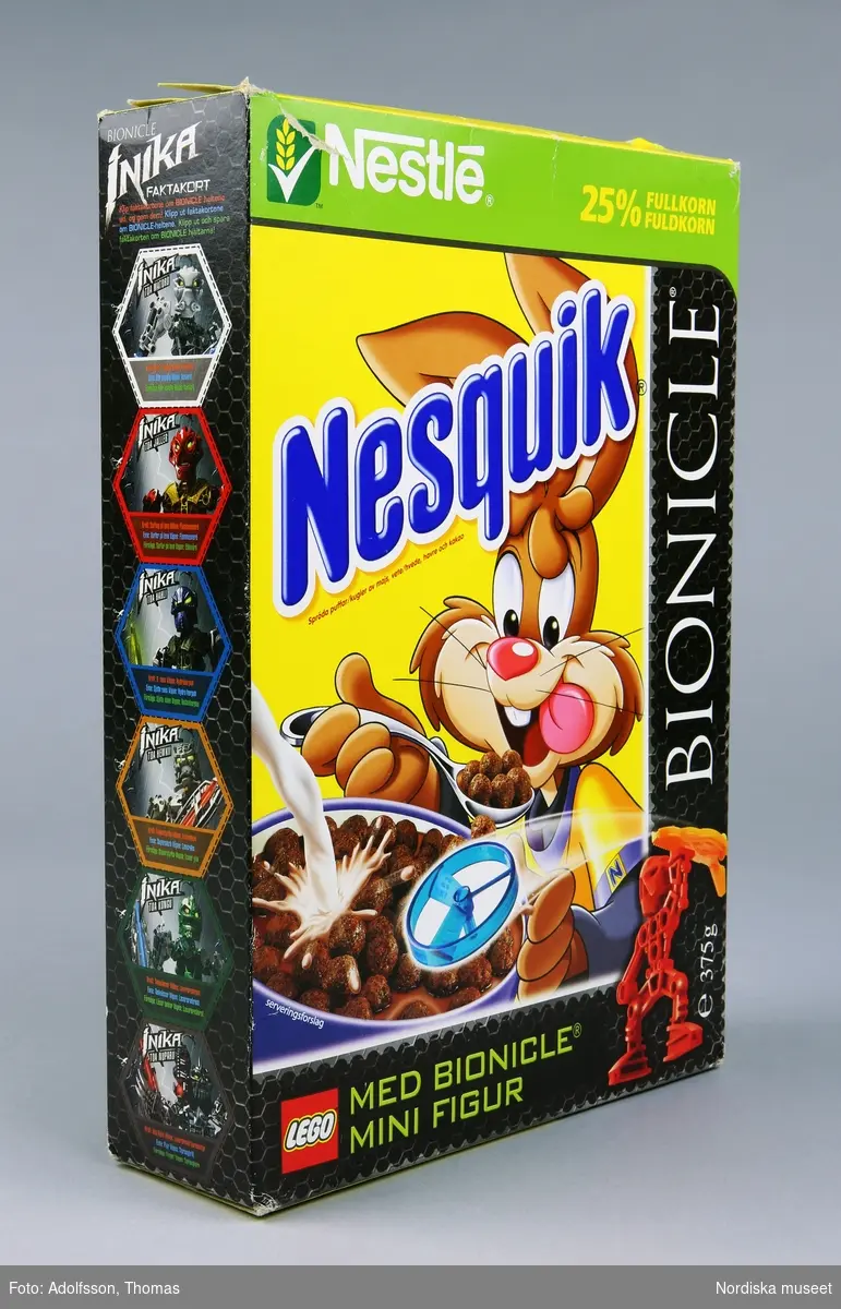 Rektangulär flingförpackning av kartong med heltäckande färgillustrationer. På framsidan en tecknad kanin som äter flingor och mjölk samt bild på en leksak (samlarfigur) som ligger i paketet. I skrift står "Nesquik Spröda puffar av majs vete, havre och kakao [...] 25 % fullkorn" samt "Bionicle [...] Med bionicle mini figur" och Legos logotyp. 

På motsatta sidan, samt på ena kortsidan, presenteras de medföljande samlarfigurerna med instruktioner om hur man leker och tävlar med dem. Se länkad fil.

Kartongen har pappersskada på ovansidans längsgående flik.