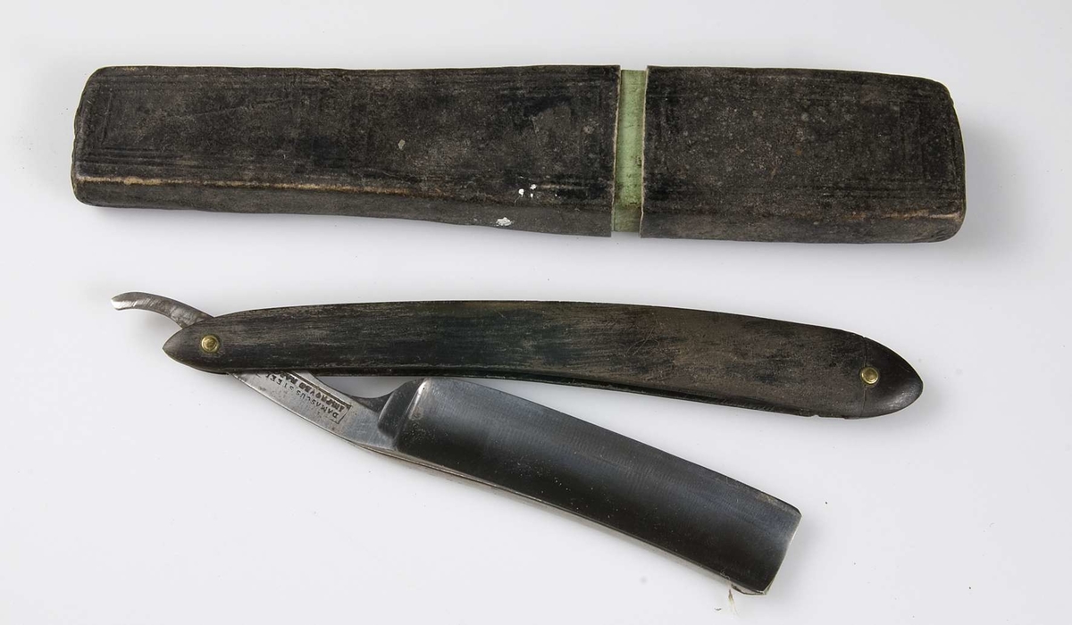 Skaft av svart horn, knivblad av stål. På knivbladet stämpeln: DAMASCUS STEEL, IMPROVED RAZOR.Fodral i svart papp, 17 x 3 cm.