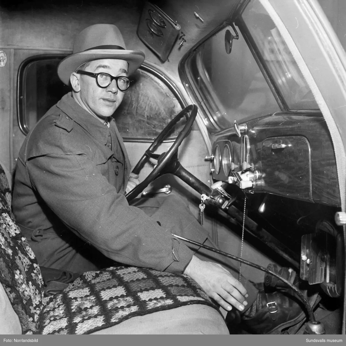 En man i en lastbilshytt med reglage för automatiska snökedjor.