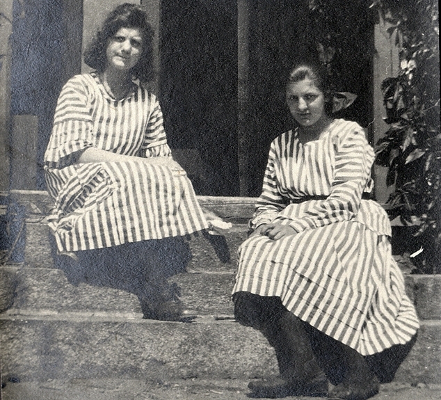 Två unga kvinnor i randiga sommarklänningar på en trappa.