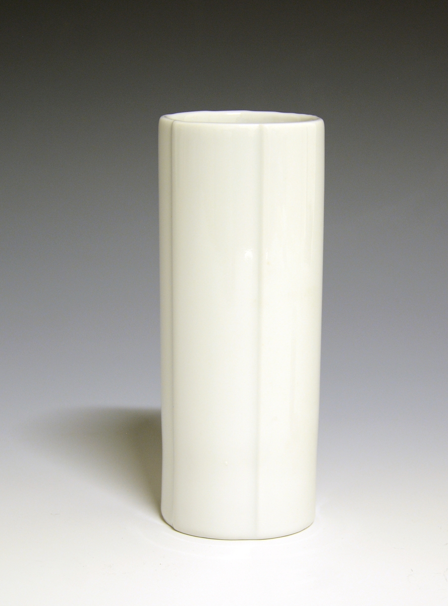 Vase og telysholder av porselen. Fungerer som vase den ene veien og telysholder den andre veien. Smal, høy sylinderform med vertikale riller. Hvit glasur. Ustemplet.
Design: Grete Rønning.