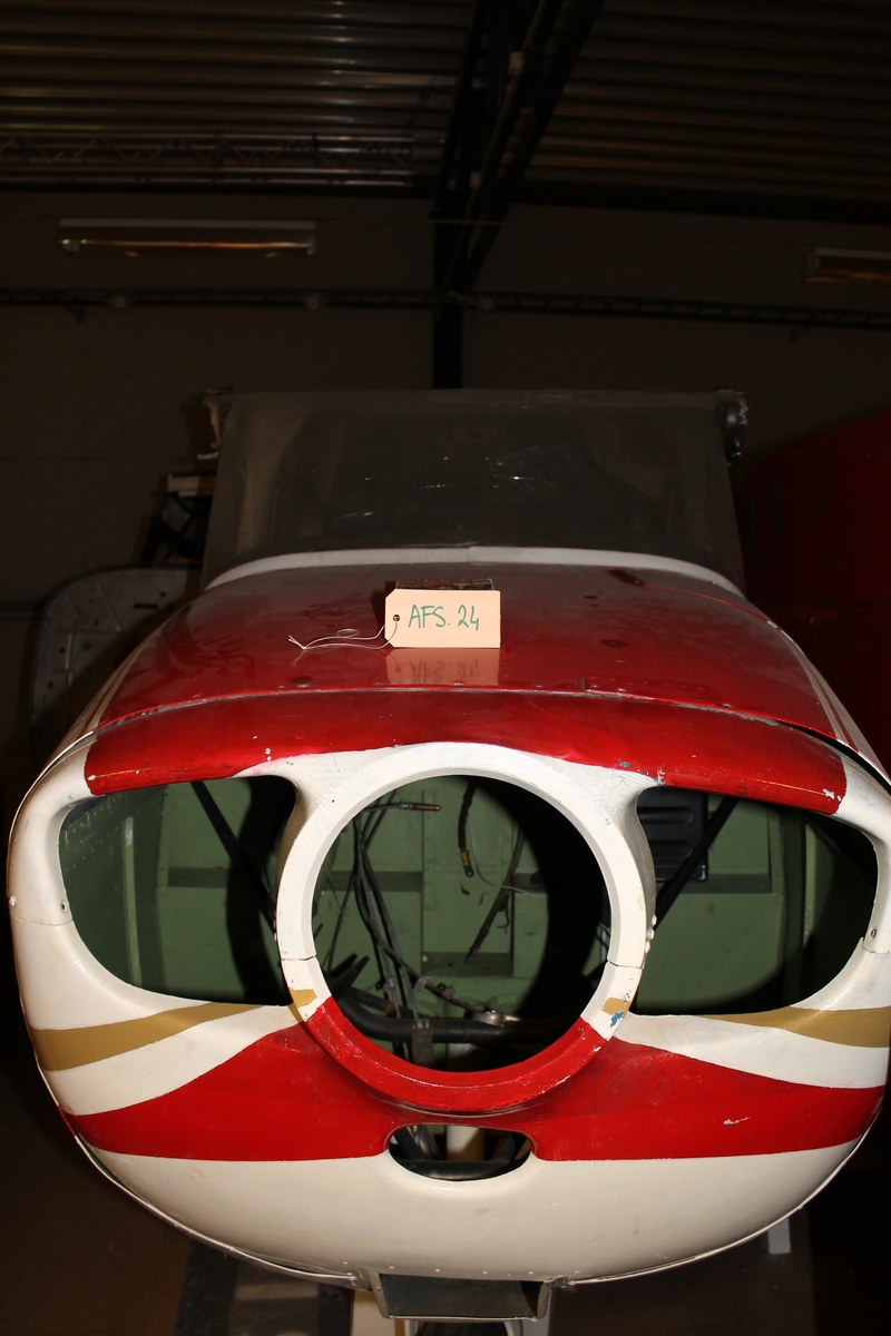 Flygplan av modell Cessna 172. Propellerflygplan bestående av flygkropp, stabilisator samt vingar. Större delen av inredningen liksom motor saknas. Vitmålat med röd och ljusbrun dekor.