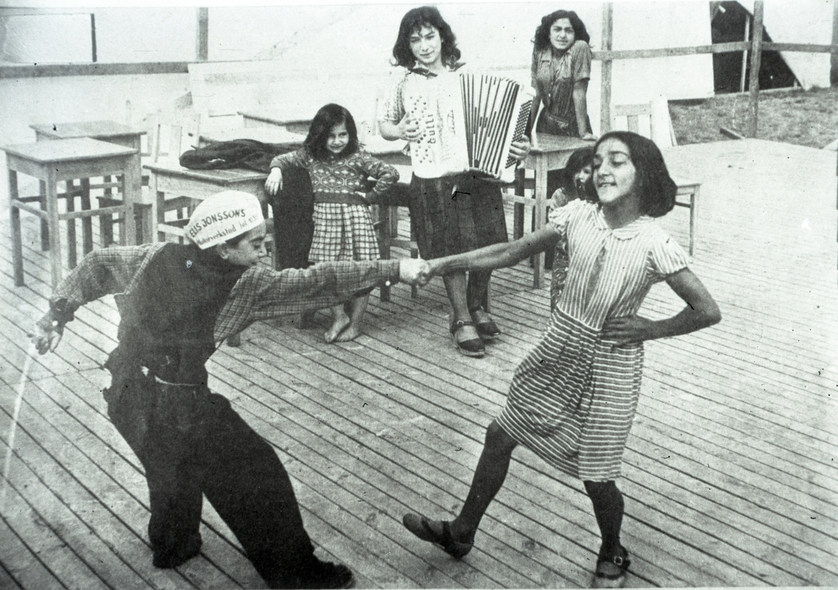 Till tonerna av dragspel dansar en pojke och en flicka på ett trädäck. Att vara musikant har historiskt varit ett vanligt yrke bland romer i Sverige, såväl som handel och försäljning av musikinstrument. Musicerandet har ofta kombinerats med tivoliverksamhet, teater eller lustspel av olika slag. Dessa verksamheter mötte en kraftig nedgång i och med tevens genomslag under 1950- och 1960-talen.
