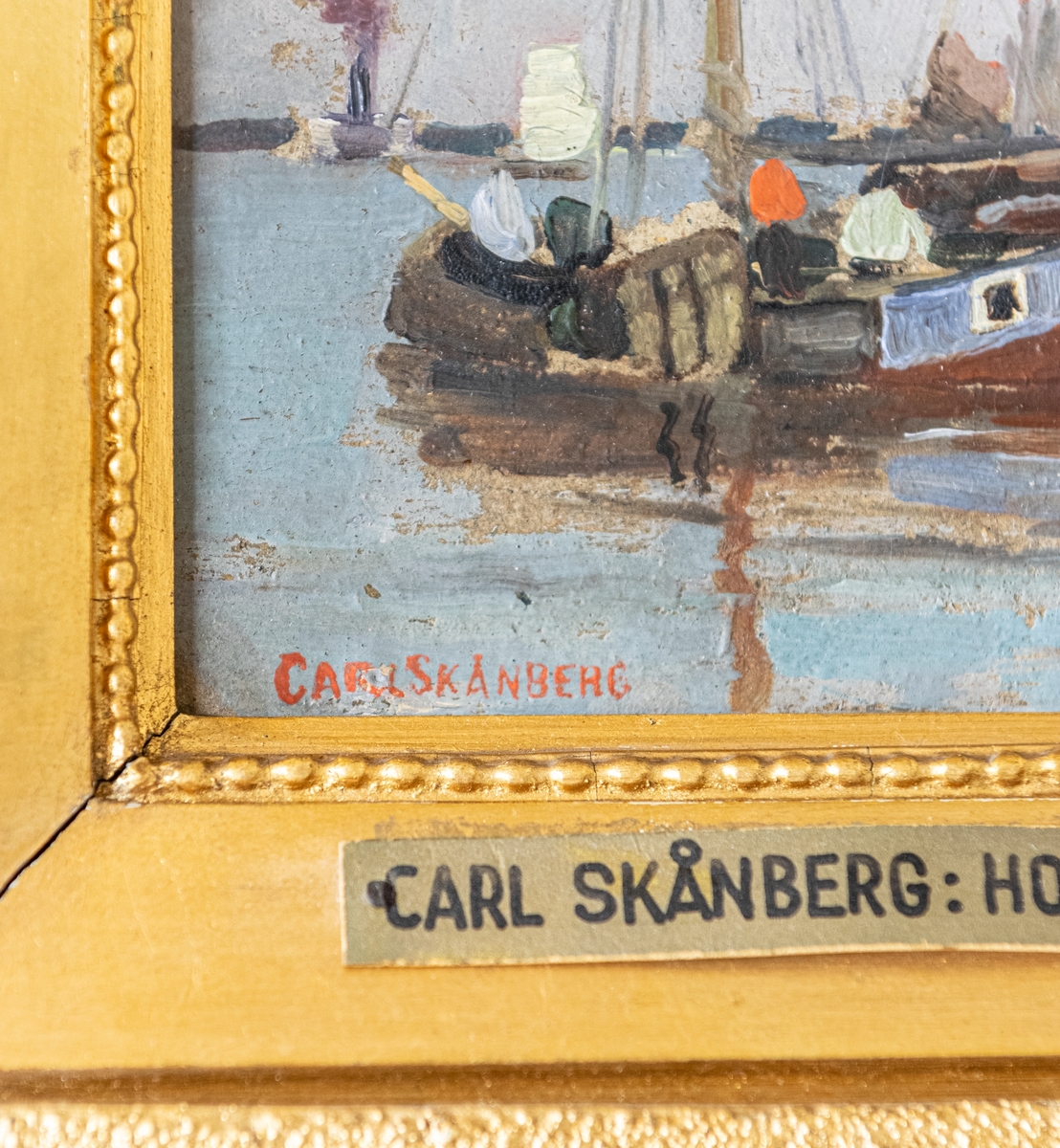 Oljemålning på pannå. Fem fiskebåtar och två jollar; samt en större seglare och en ångare i bakgrunden.
Bronserad originalram.