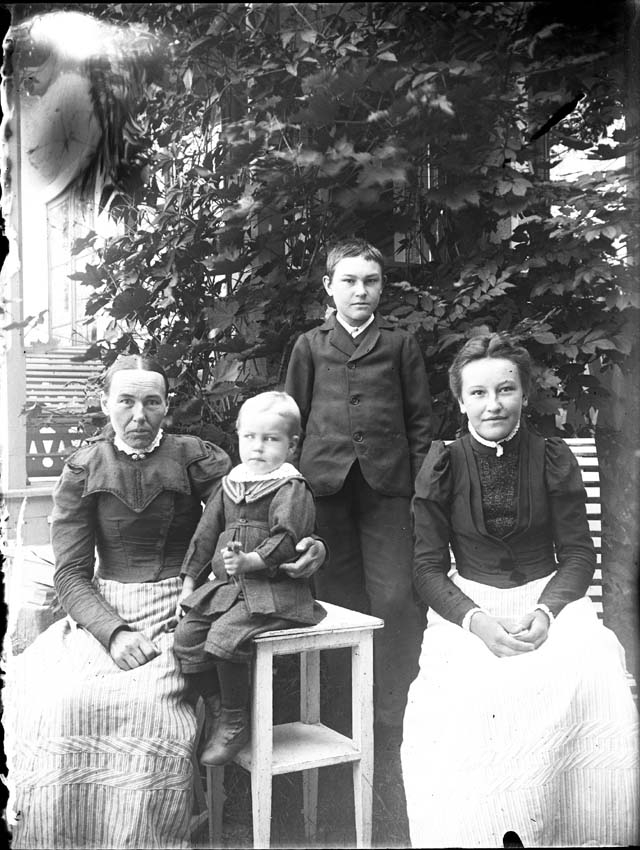 Två damer och två barn i trädgården, ca 1910.