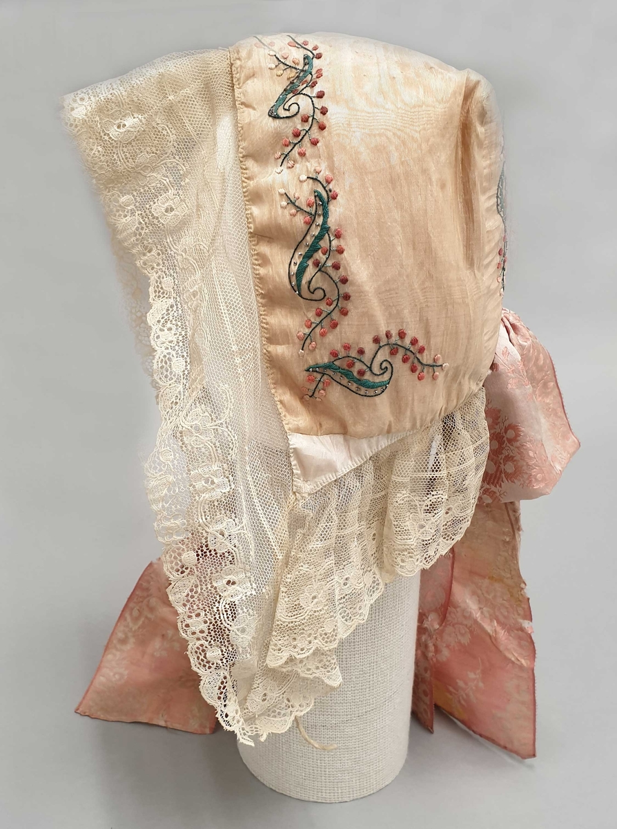 Kyse av gul silke med broderi og perlebroderi, med kniplingsblonde langs kantene, og rosa silkesløyfe.