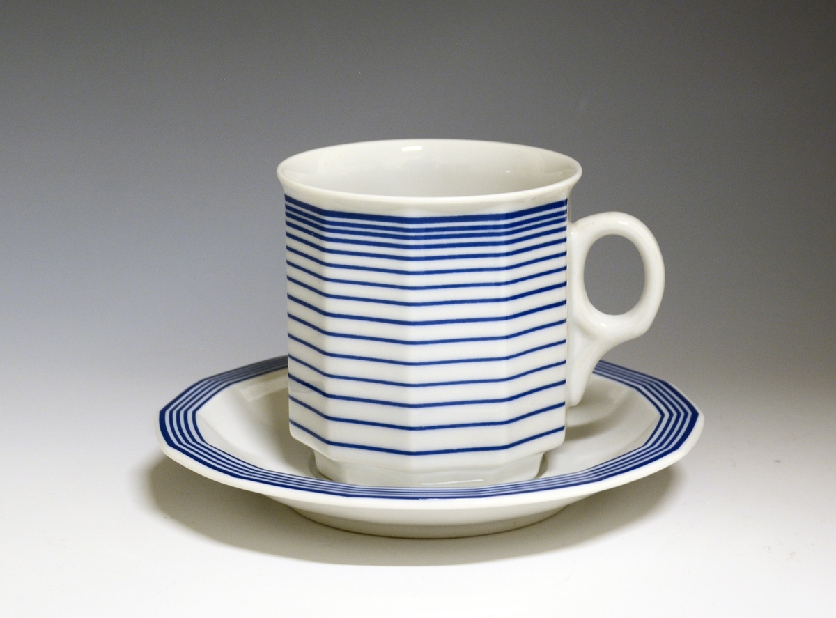 Mangekantet kopp i porselen med blå, horisontale streker som dekor. Strekene blir tettere mot øvre del av korpus.
Modell: Octavia, tegnet av Grete Rønning i 1977.
Dekor: Parallell
