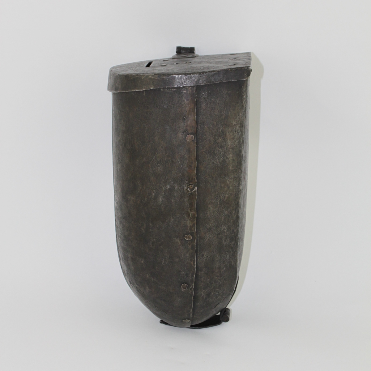 Brevbehållare eller kassaskrin av järnplåt med formen av en halvcylinder.
Lås i lock på gångjärn på ovansidan.