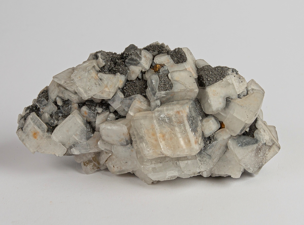 Aggregat med krystaller av kalsitt. Noen av kalsittkrystallene har belegg av små, grå mineralkorn.
Gottes Hülfe in der Noth, 150 m.