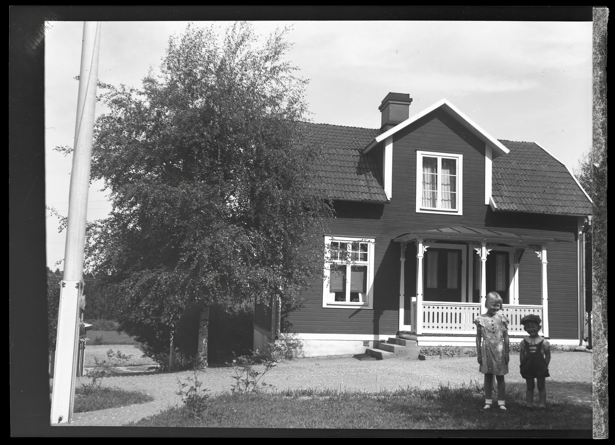 Två barn framför ett hus.