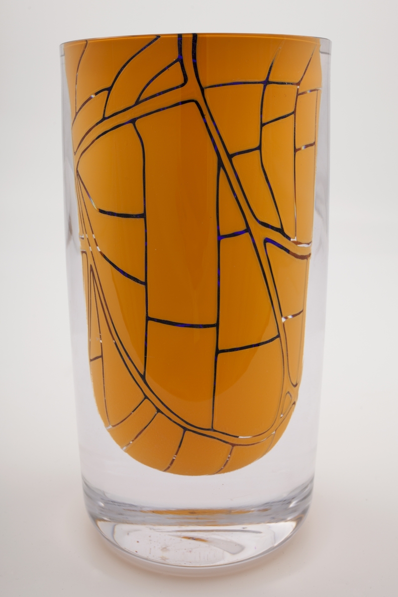 Massiv sylinderformet vase i underfangsglass, bestående sjikt i dyp blått, klart og orangefarget glass. Det orange sjiktet er delvis fjernet, slik at det blåfargen kommer til syne i form av geometriske linjeføringer. Planslipt topp og sirkulær åpning.