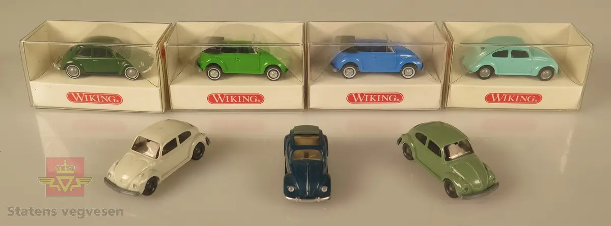 Samling av flere modellbiler. 3 biler er grønne, 3 biler er blå og 1 bil er hvit. Alle er laget av plast og har en skala på 1:87