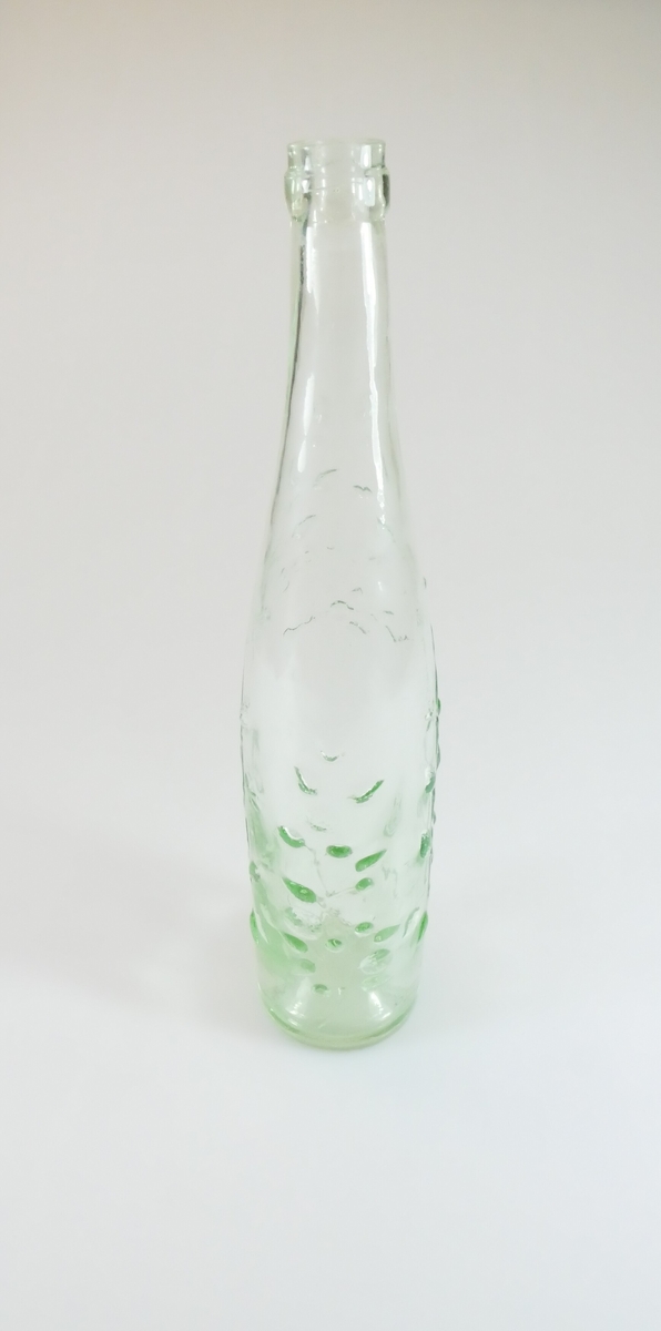 Klar glassflaske med grønskjær og bladmotiv. Flasken smalner øverst til en tut. 
