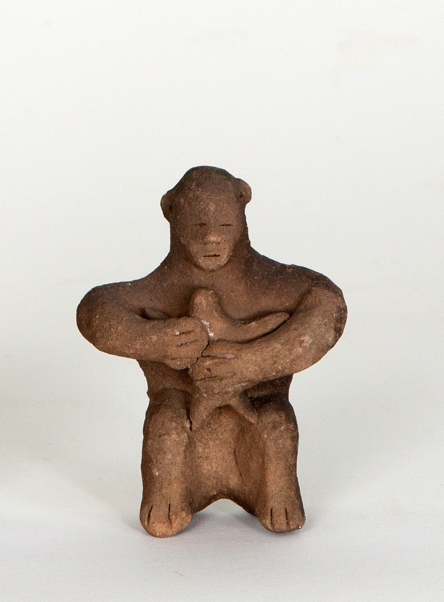 Figurin i leirgods, fremstiller en stilisert menneskeskikkelse med barn i armene, muligens ammende.
