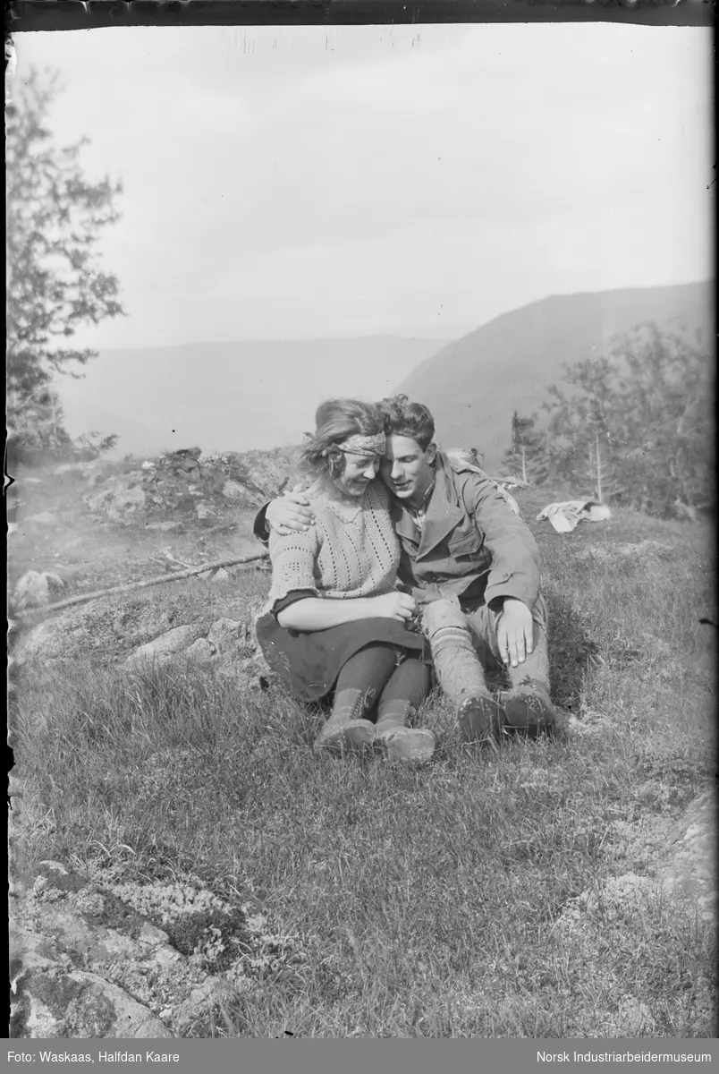 Kvinne og mann sittende tett omslynget på fjellet.