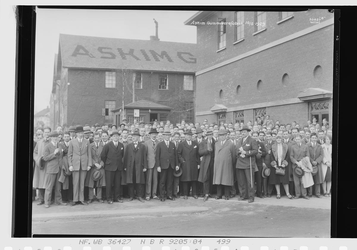 Gruppe mennesker fra bla. Handelsgymnasiet foran fabrikkbygning, Askim gummivarefabrikk A/S. "Askim Gummivarefabrikk 156/5-1929".
