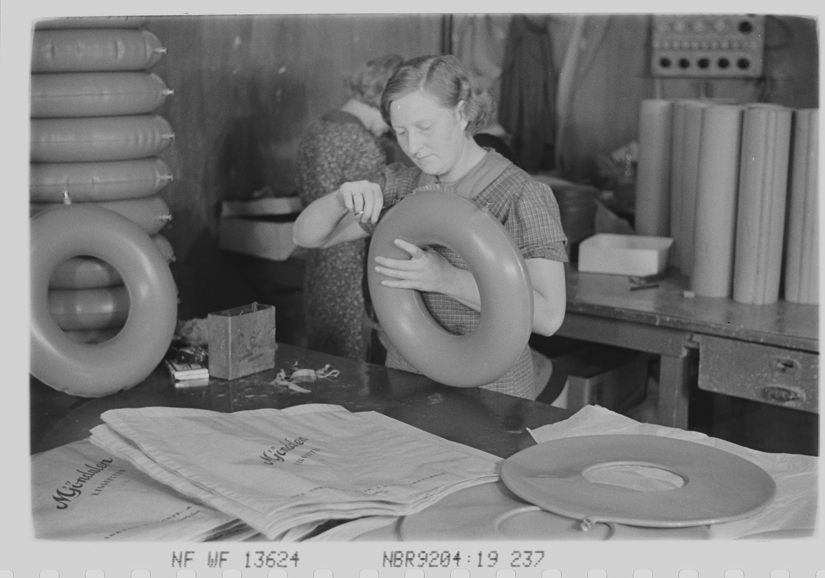 Kvinnelig ansatt med produksjon av baderinger. Den Norske Kalosje- & Gummivarefabrikk A/S, senere Mjøndalen Gummivarefabrikk, Eiker. Fotografert 1940.