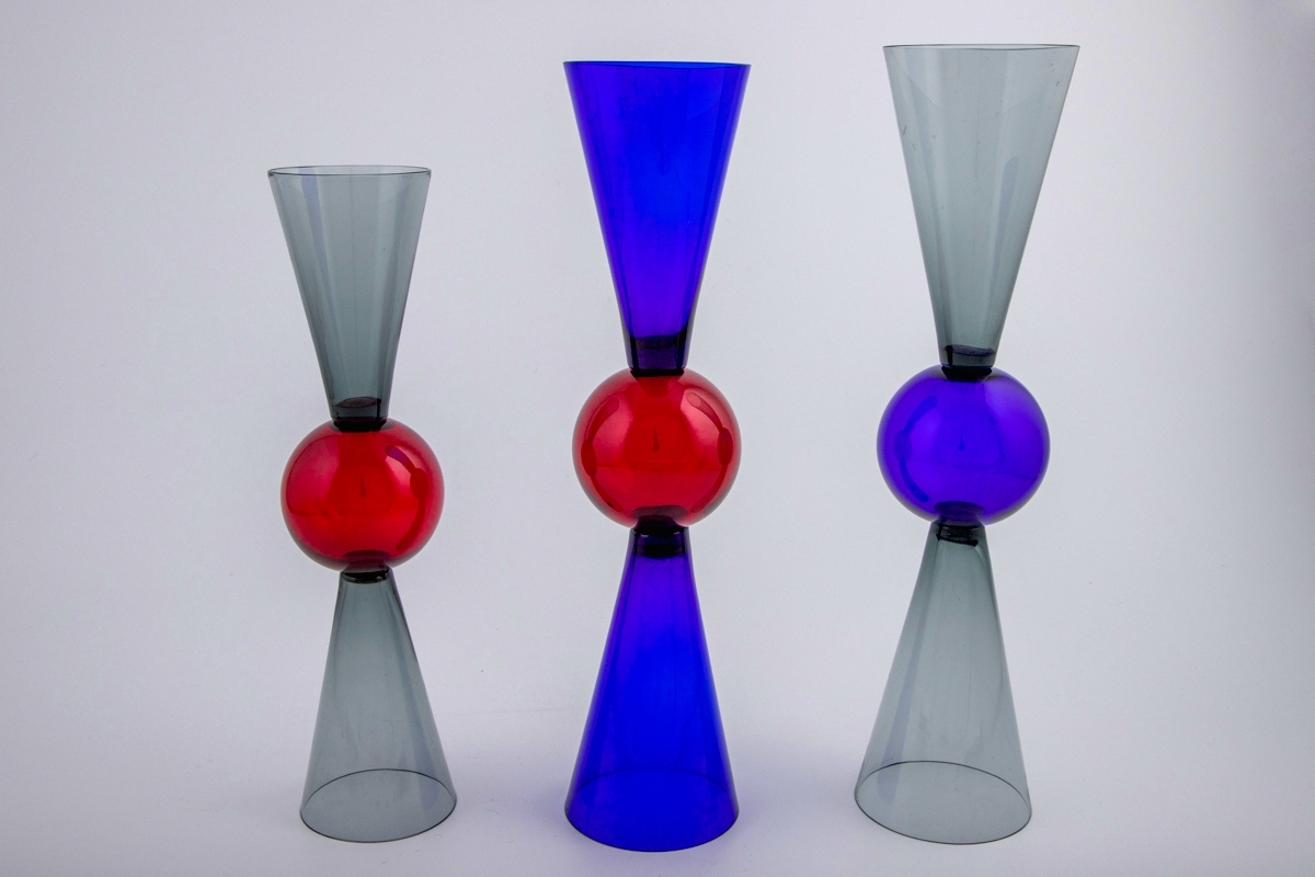 Tre vinglass utført i farget gjennomskinnelig glass. Glassene er utført i tre ulike størrelser. Kupa og fot er konisk utformet, og smalner mot glassets midtparti som er markert med en kule. Dermed kan begge sidene fungere som fot og klokke.