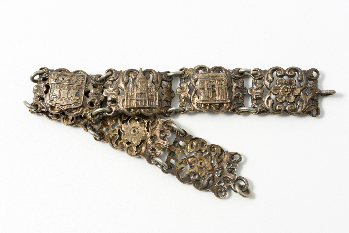 Armbånd i metall dekorert med motiv av blomster og kulturminner/landemerker (f.eks. eiffeltårnet og triumfbuen)