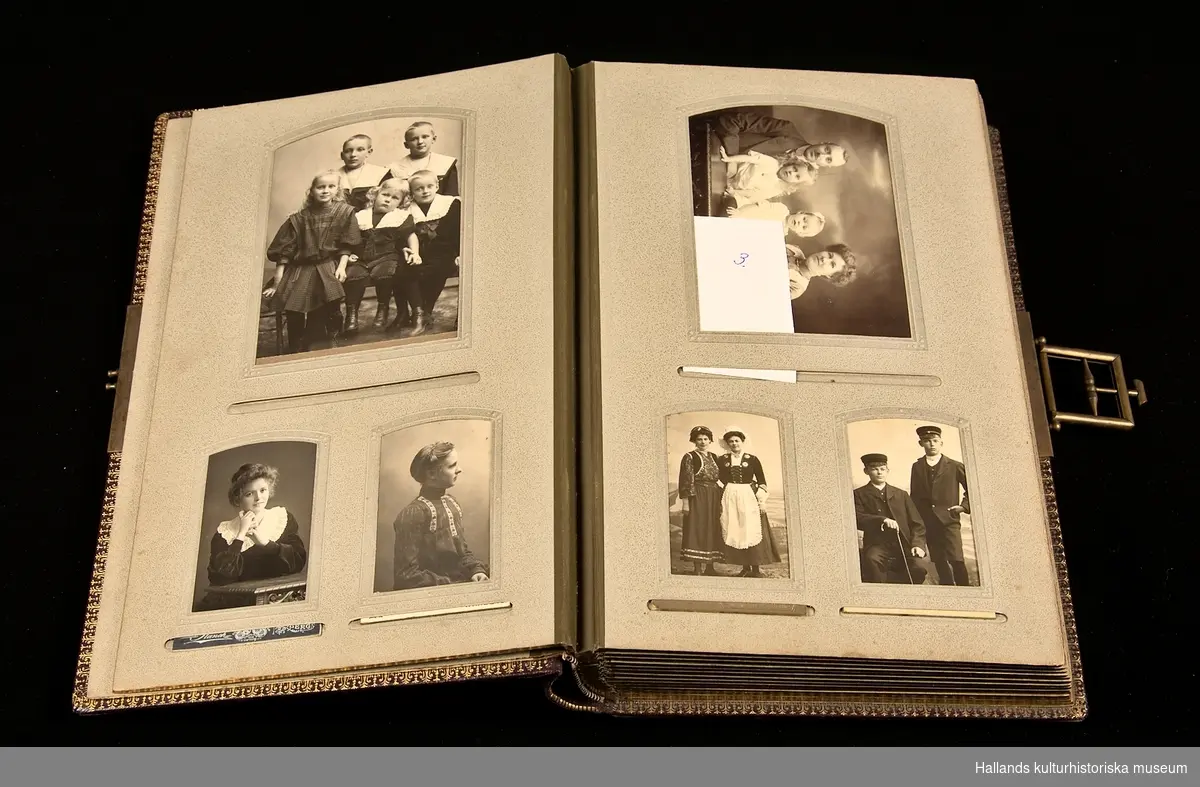 Vinrött fotoalbum (a) i svart låda (b) innehållande fotografier från tiden 1890-1930. Lås i mässing. Arken guldfärgade på kanterna.