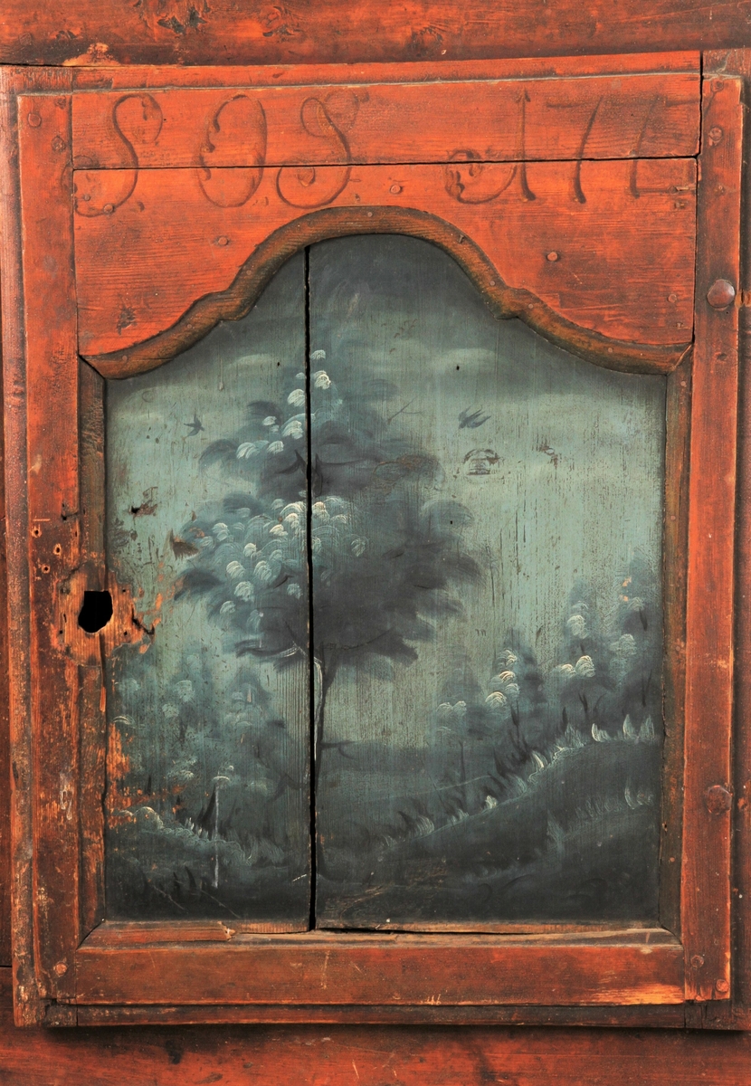 Skap med låsbar dør og tre hyller innvendig. Brunmalt på rammene rundt speilet i døra og feltene på hver side og over døra. Feltene og dørspeilet er dekorert med trær og landskap i blåfarger.