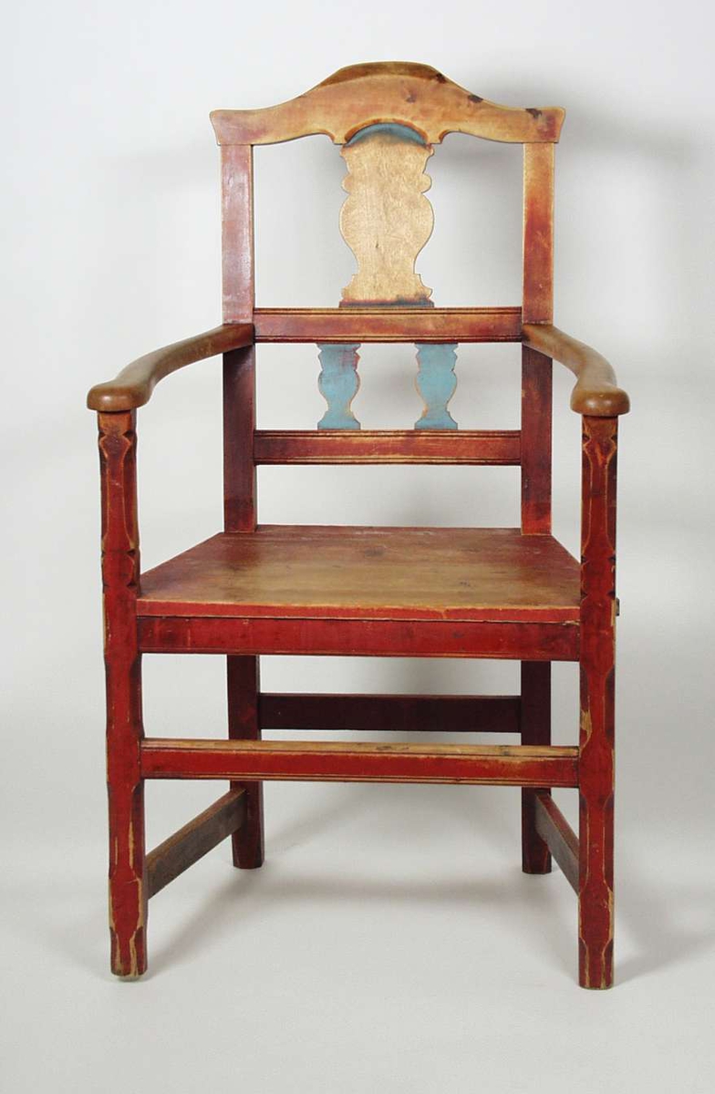 Armstol med sprosser i ryggen. Stolen er malt rød med blå sprosser. Malingen er slitt. Setetrekket er slitt i stykker i forkant. Trekket har striper i grått, rødt, blått og gult. 