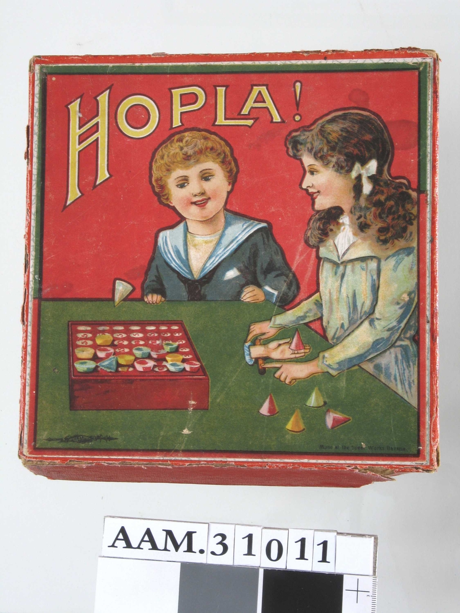 På eske: Jente og gutt ved et bord, leker med et Hopla-spill.