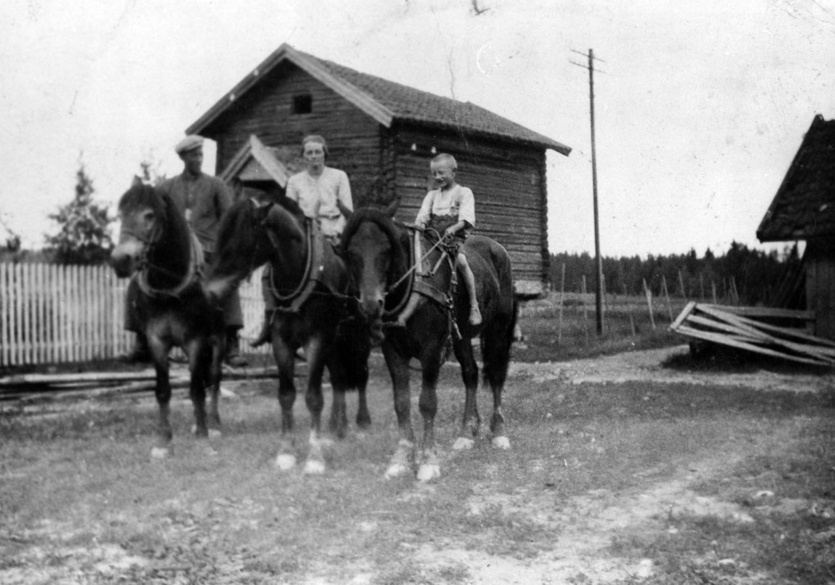 Tre ryttere på gardsplassen på nedre Nesten. Mann, kvinne og gutt til hest.