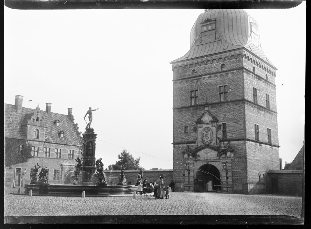 Fredriksborg Slott, Danmark. Slottet sett uienfra. En stor fontene med flere mennesker rundt.