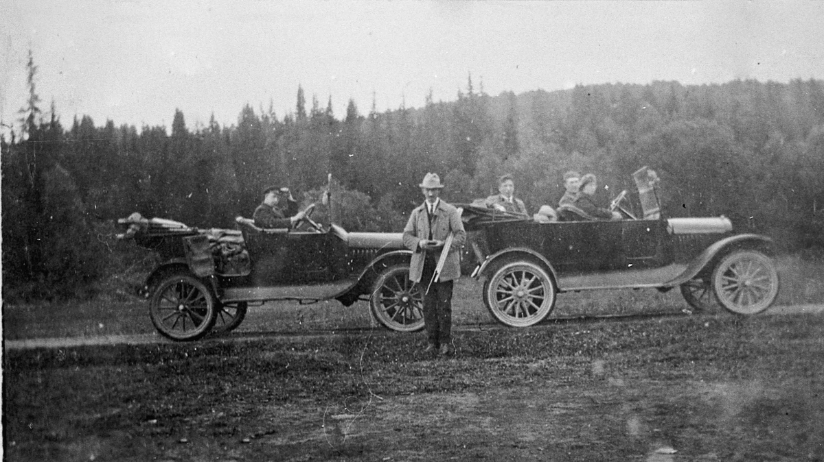 2 biler av mellomkrigsmodell. Skrukklia 1926.
I bilen til venstre: Peder Lesja ved rattet. Amund Millidal står foran. I bilen til høyre: Jacob og Hjørdis Millidal i forsetet. Nicolai Tronsbråten bak. Bilen til høyre ble brukt som drosje.
