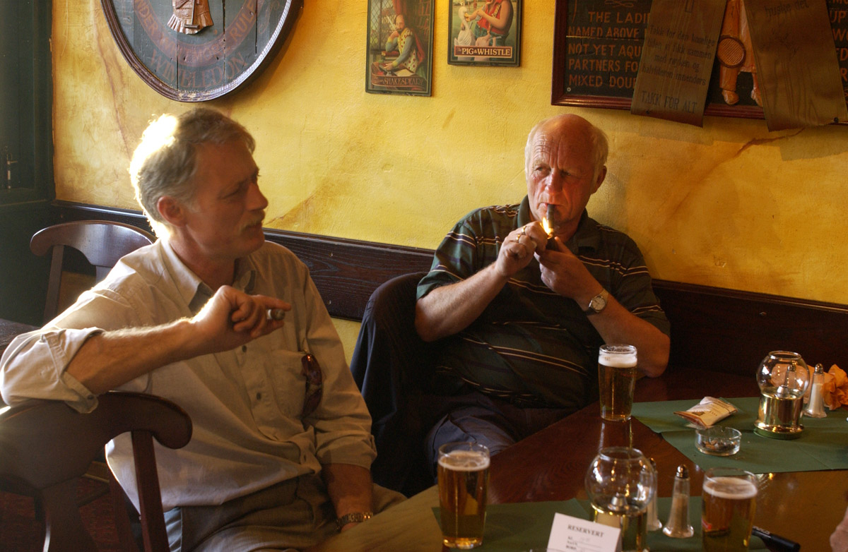 2 menn ved et bord med sigar og tobakkspung. Bowler & Spisepub.
