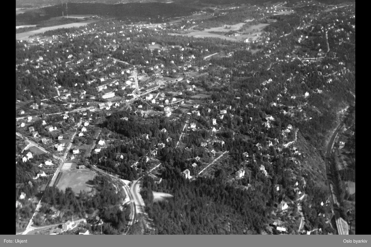 Småhusbebyggelse, Østfoldbanen til høyre, Ekebergbanen, skog og jordbruk i bakgrunnen, Aker (Flyfoto)