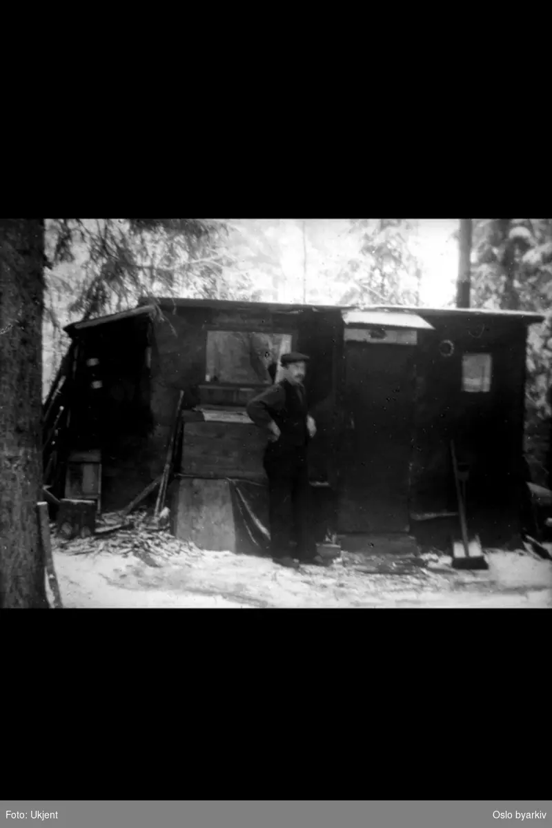 Provisorisk hytte i Abildsøskogen med mann ved inngangen