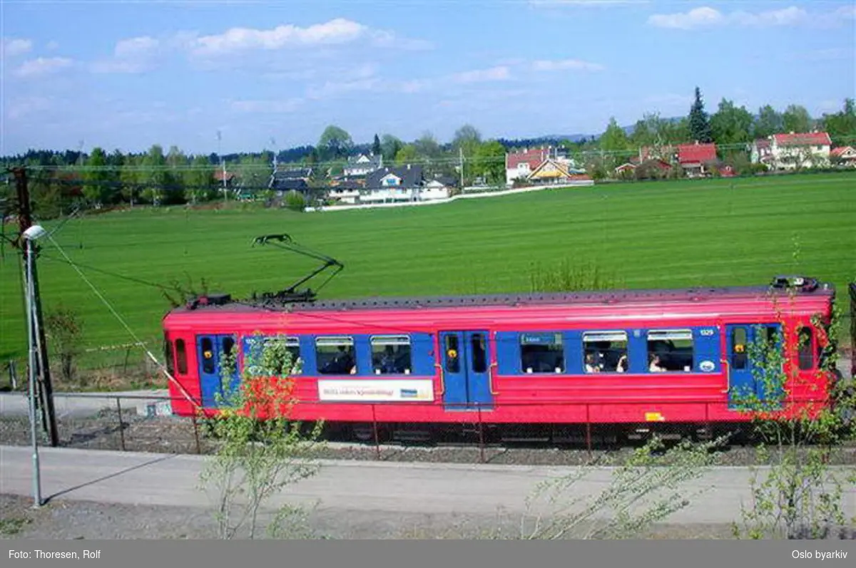 Oslo Sporveier. Kolsåsbanen. T-banevogn 1329, serie T6, på linje 4 langs Gjønnesjordet. Gjønnes gård i bakgrunnen.