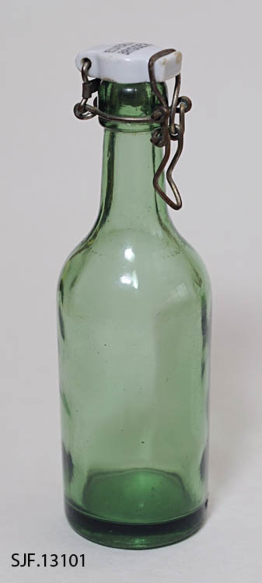 Flaske av grønt glass, antakelig opprinnelig brus- eller ølflaske, som kan ha vært gjenbrukt til aldre drikkevarer, for eksempel husholdningssaft. Flaska er 20,0centimeter høy (uten kork). Den har en sylindrisk kropp med cirka 6,7 centimeters diameter. Cirka 11 centimeter fra standflata går den sylindriske delen over i ei innoverskrånende skulder mot en mer sylindrisk hals. Den midtre delen av flaskebotnen er oppoverkuvet. Flaska kan romme cirka 3 desiliter væske. Godset omkring munningen - «flasketuten» - er noe tjukkere enn i flaska for øvrig, og her er det et spor som har gitt feste for en såkalt «patentkork». Dette er en propp, utført i kvitt porselen, som er hengslet til flasketuten ved hjelp av ståltråd, som er forankret i det nevnte sporet omkring flasketuten slik at proppen faller ned i flaskemunningen og kan låses der ved hjelp av ei ståltrådspenne, som når flaska lukkes omslutter en tapp i den fremre enden av porselenselementet. Undersida av denne komponenten har vært utstyrt med en rødfarget gummipakning, som skulle skape et vakuum i flaska. Her er pakningen bare delvis intakt. Oversida av porselenselementet er merket «ELVERUM BRYGGERI» (jfr. fotografiet SJF-F.013394).