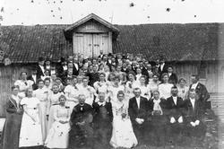 Stor gruppe bryllupsgjester oppstillt på låvebrua på Mølstad