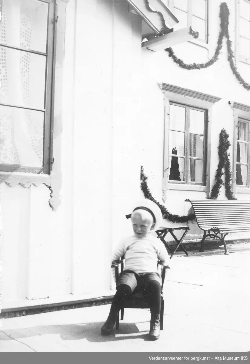 Kronprins Olav sitter fremfor pyntet bygning, Alteidet 1907