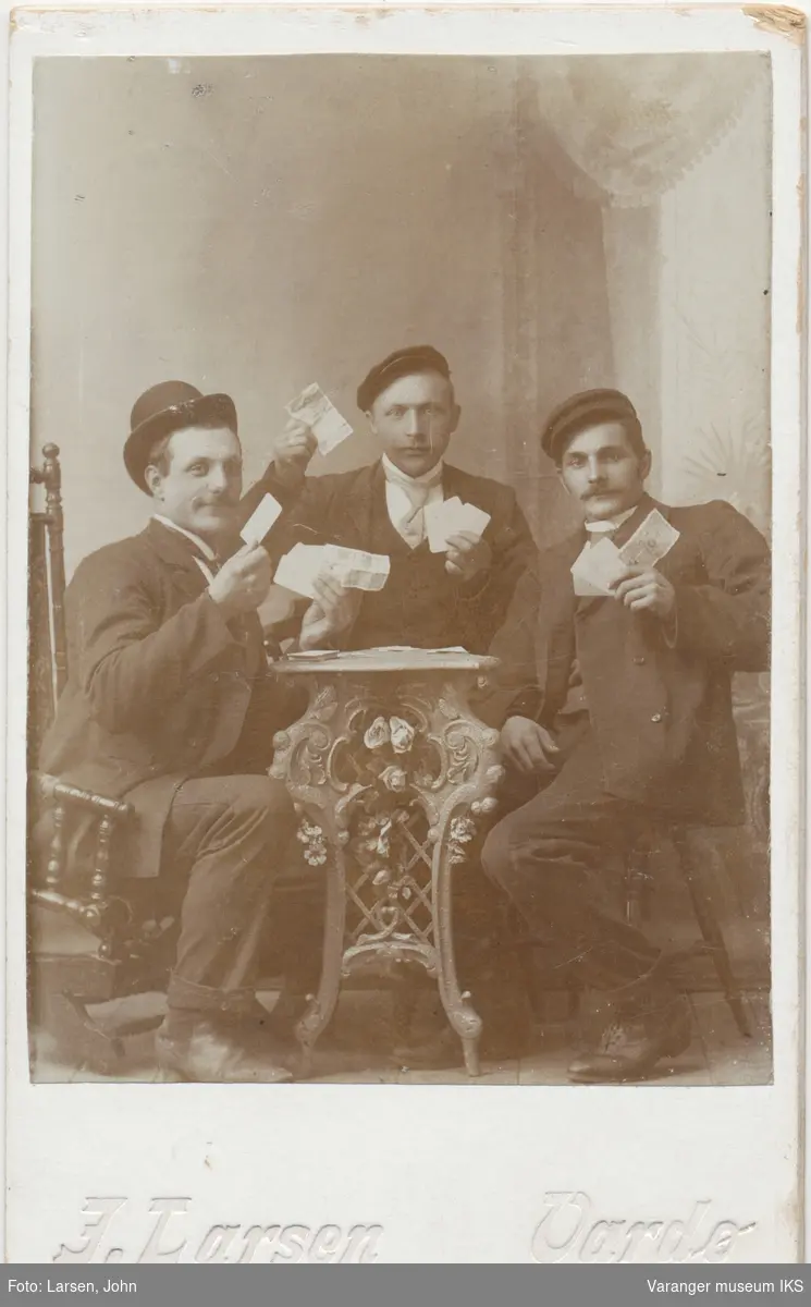 Gruppeportrett, tre menn poserer med kort og pengesedler