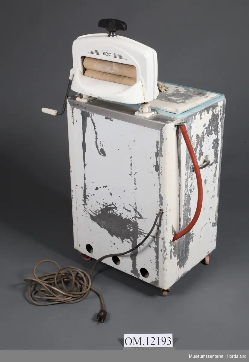 Pulsatormaskin (vaskemaskin) med rulle og lok. Merke: Hobby. Rulle har merke Fresco, og er montert oppå på maskinen. Kvitmåling flassar av. Hobby-merket frampå er nesten vekke. Lok med handtak med surra fille rundt.Produsert 1950-talet?