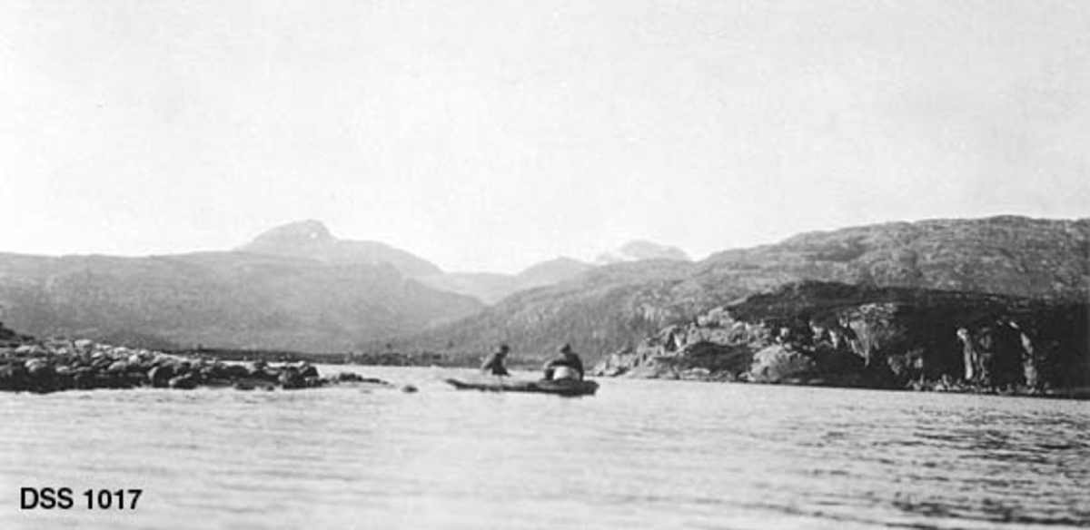 Garnfiske på Hundålvatnet i Vefsn.  Fotografiet viser to menn i en robåt, like utenfor ei steinur.  I bakgrunnen berg- og fjellrygger. 