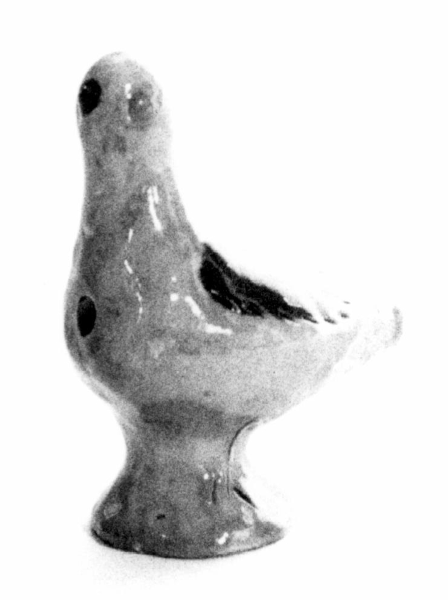 Spaltefløyte i keramikk i form av en fugl, utvendig med gulbrun glasur, vinger og nebb med brun glasur.
Spalte og labium i stjerten, ett fingerhull i brystet.