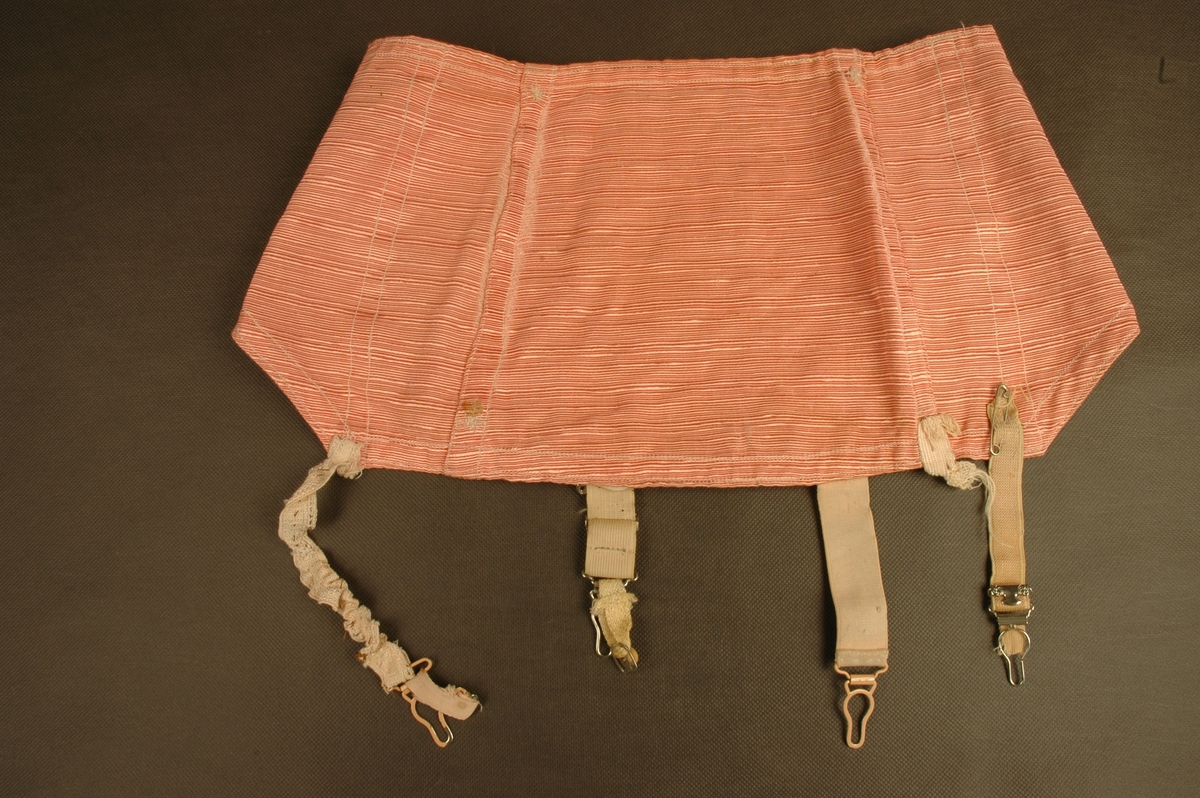 Rosa hofteholder med fire stropper for feste av strømper, to foran og to bak. Lukkes i venstre side med ni hekter. Sydd sammen av bakstykke, to sidestykker og forstykke. Felt med strikk foran på hvert sidestykke.