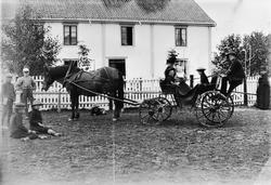 Gruppe ukjente barn og voksne utenfor ukjent bygning. Hest m