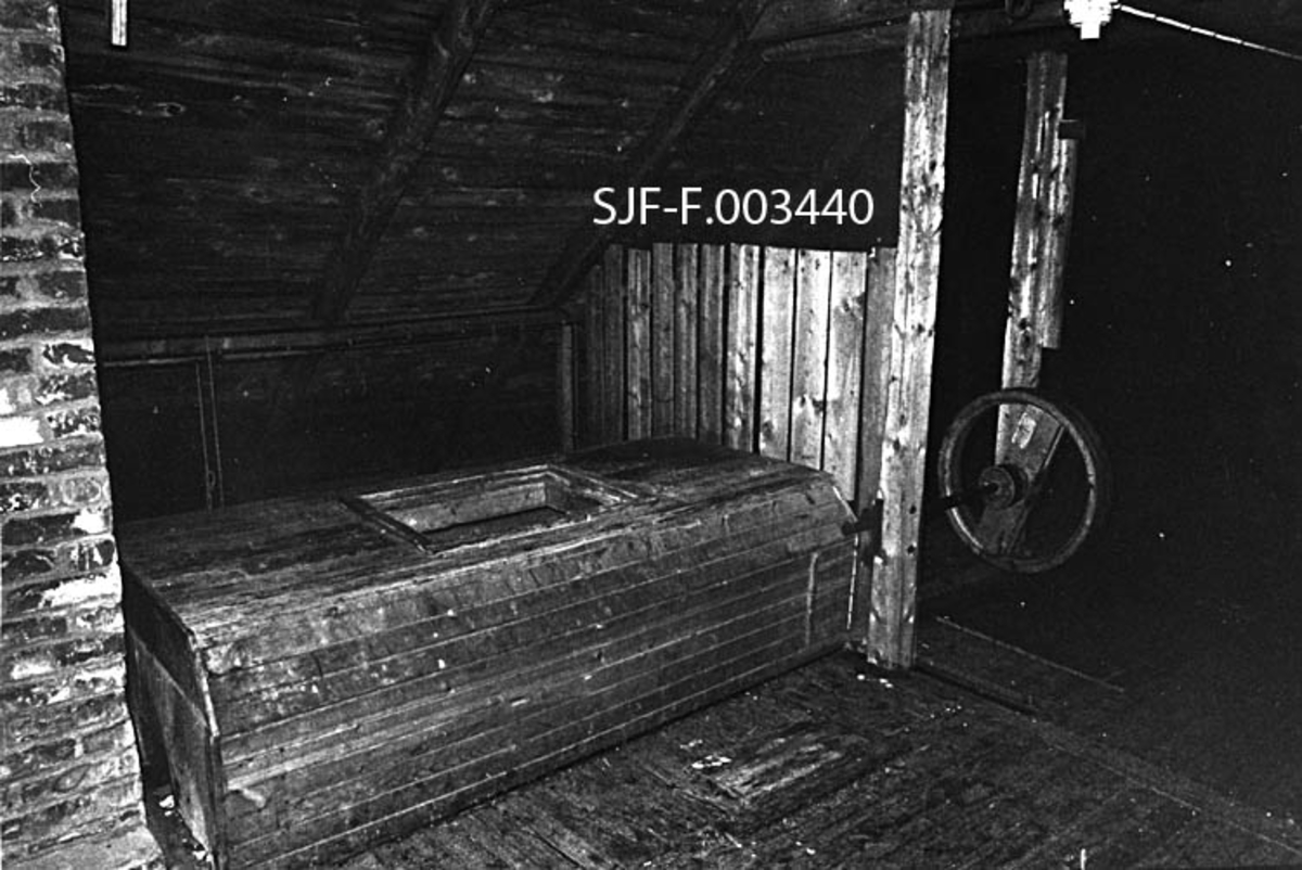 Fra loftet over klengstua i Målselv i Troms.  Fotografiet er tatt i 1980, mange år etter at skogfrøproduksjonen her opphørte.  I den perioden klengstua var i drift ble loftet brukt som konglelager.  Bildet viser en del av innredningen som antakelig ble lagd i forbindelse med ei modernisering av anlegget som ble utført i forbindelse med et par, i nordnorsk målestokk, sjeldent gode frøår for furu i andre halvdel av 1930-åra.  Sentralt i bildet ser vi en slags kisteformet trekonstruksjon med en rektangulær åpning i loftet.  Gjennom denne åpningen kunne en tømme innholdet i konglesekker ned i en underliggende kongletrommel, som var opplagret på en aksling i den avbildete bordkista.  Til høyre for denne konstruksjonen, mellom to stolper, ser vi ei av flere reimskiver for transmisjon av kraft fra en motor som ble installert for å drive kongletromlene og en rensemaskin.  Helt til venstre i bildet ser vi teglsteinspipa fra ildstedet i det underliggende klengrommet. 