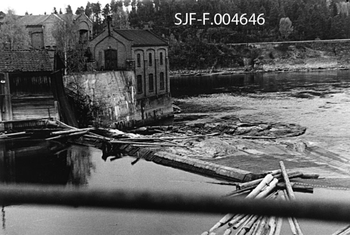 Geithusfossen på Modum i Buskerud, slik den så ut 21. oktober 1945, på et tidspunkt da vannføringa i Drammenselva var ekstremt lav (33 kubikkmeter per sekund).  Fotografiet er tatt i medstrøms retning (akkurat her renner elva nordover) med terskelen som var bygd like ovenfor det øverste fallet i fossen i forgrunnen.  Helt til venstre i bildet lå det en dårlig vedlikeholdt trebygning med krumsteinstak.  Bakenfor ser vi noe av teglsteinsbebyggelsen ved Drammenselvens Papirfabrikker med det huset som rommet fabrikkens likestrømstasjon nærmest vassdraget og fossen.  I Hontvetåsen i bakgrunnen skimter vi Randsfjordbanens trasé. 